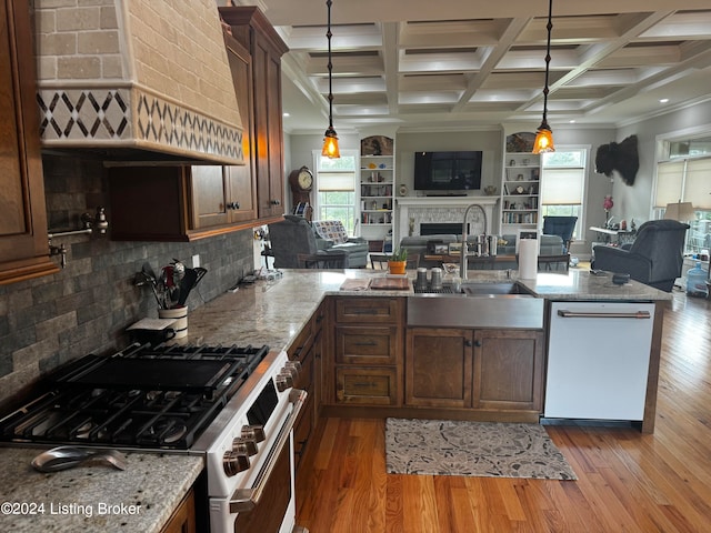 kitchen featuring sink, light wood-type flooring, stainless steel appliances, decorative light fixtures, and custom exhaust hood