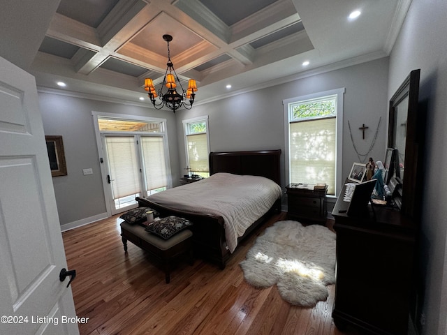 bedroom with coffered ceiling, ornamental molding, an inviting chandelier, and hardwood / wood-style floors