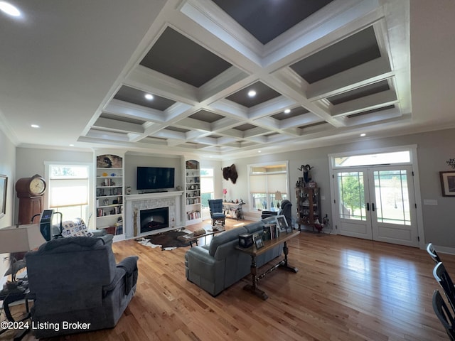 living room with coffered ceiling, wood-type flooring, ornamental molding, and plenty of natural light