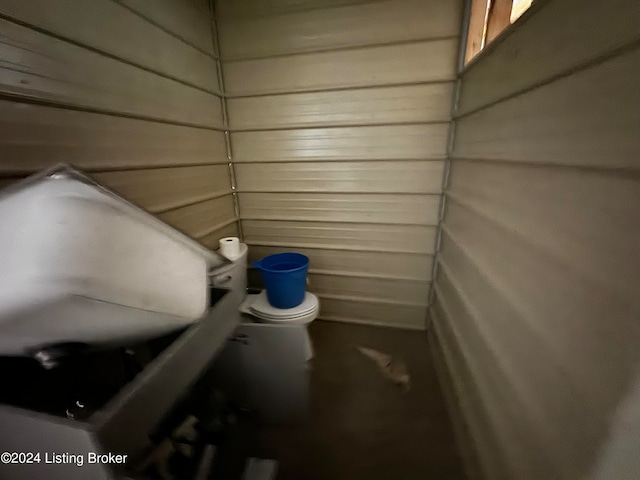 bathroom with toilet and wood walls