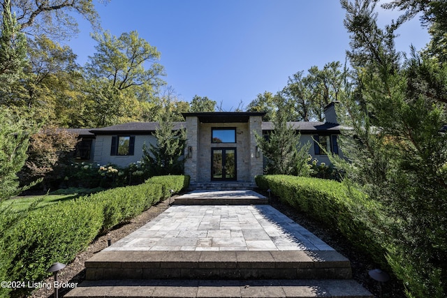 view of front facade featuring french doors and a chimney