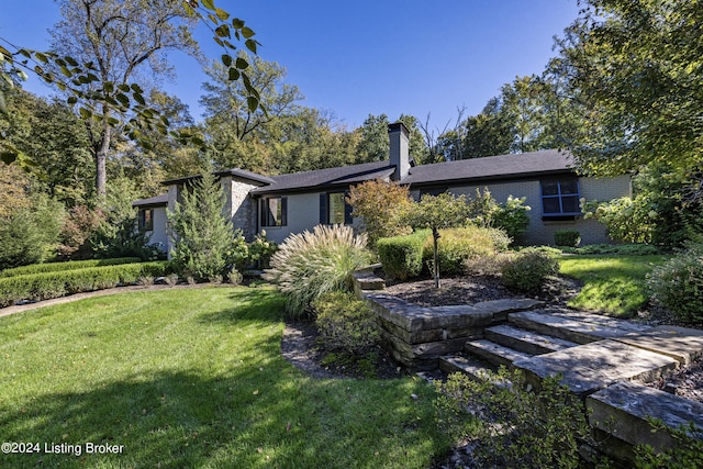 view of front of house featuring a chimney, a front lawn, and brick siding