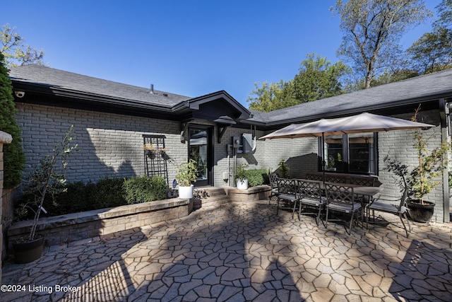 back of property with outdoor dining area, brick siding, and a patio