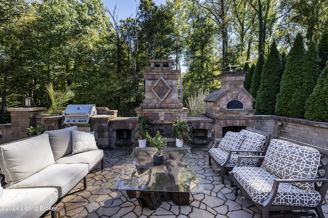 view of patio with an outdoor living space with a fireplace, an outdoor kitchen, and area for grilling