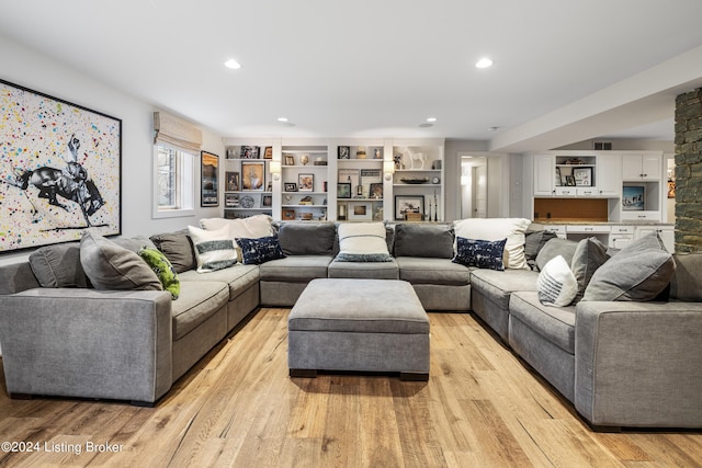 living room with light wood-type flooring, recessed lighting, visible vents, and a stone fireplace