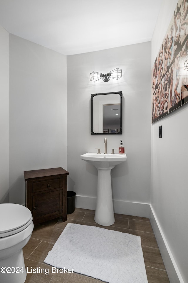 half bathroom with toilet, wood tiled floor, and baseboards