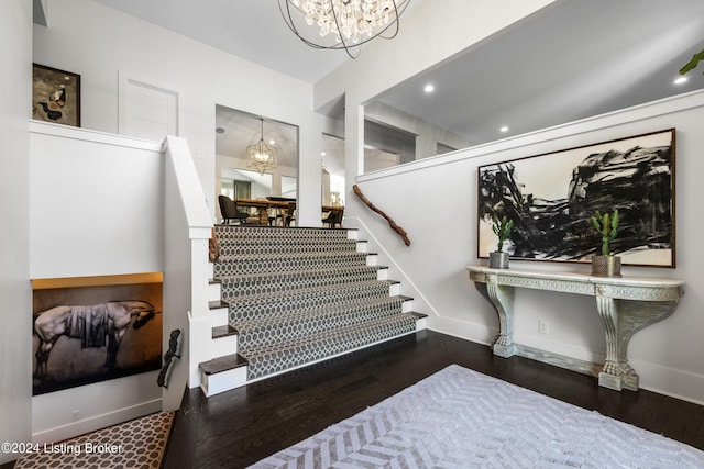 staircase with a notable chandelier, baseboards, and wood finished floors