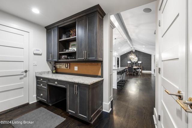 bar featuring vaulted ceiling with beams, baseboards, built in desk, and dark wood-style flooring