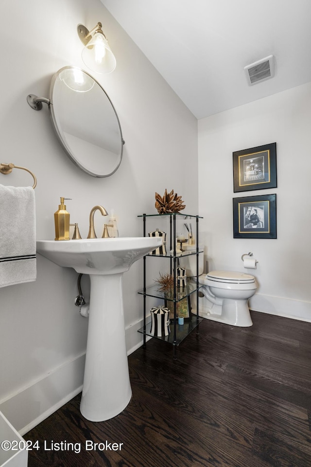 half bathroom featuring toilet, wood finished floors, visible vents, and baseboards