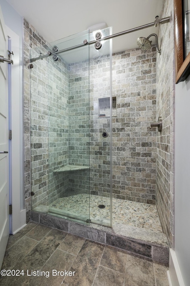 full bathroom with stone finish flooring and a shower stall