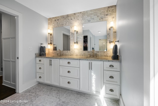 bathroom featuring tasteful backsplash, a sink, baseboards, and double vanity