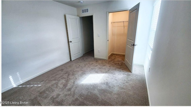 unfurnished bedroom with a spacious closet, carpet floors, and a closet