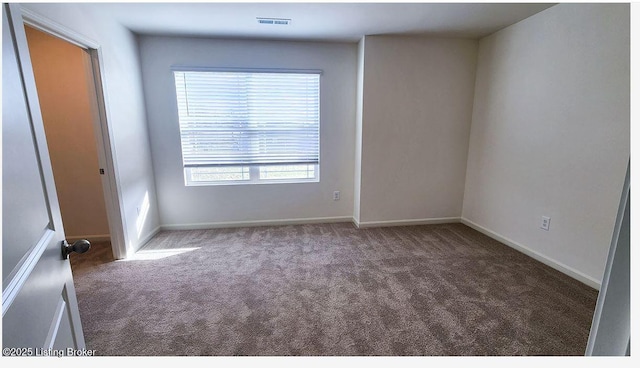 spare room featuring dark carpet