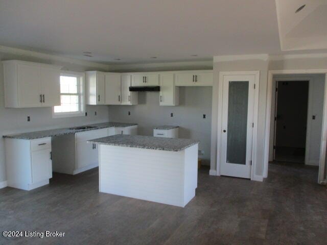 kitchen with sink, a kitchen island, white cabinetry, and light stone counters