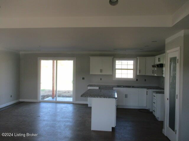 kitchen with a kitchen island, white cabinets, and dark stone countertops