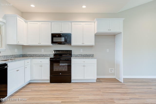 kitchen with light stone counters, light wood-type flooring, black appliances, and white cabinetry