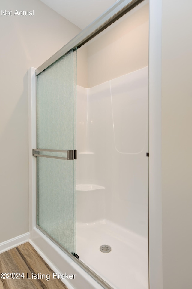 bathroom with wood-type flooring and a shower with shower door