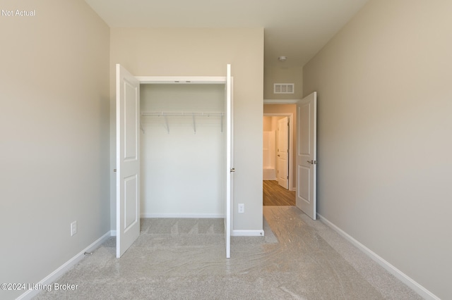 unfurnished bedroom with a closet and light carpet