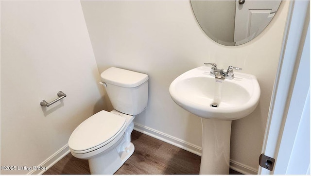 bathroom with toilet, wood finished floors, and baseboards