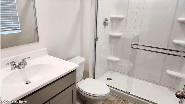 bathroom with a shower stall, toilet, and vanity