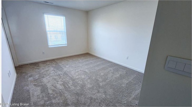 carpeted empty room featuring visible vents and baseboards