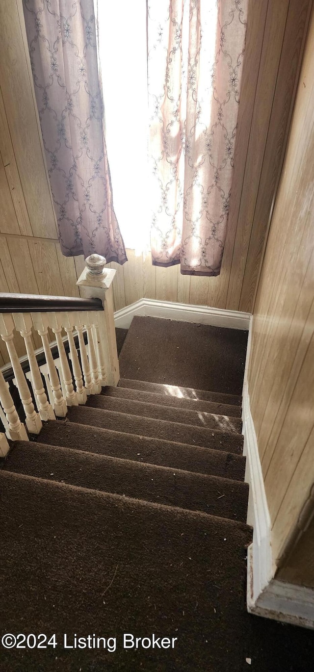 staircase featuring wooden walls and radiator heating unit