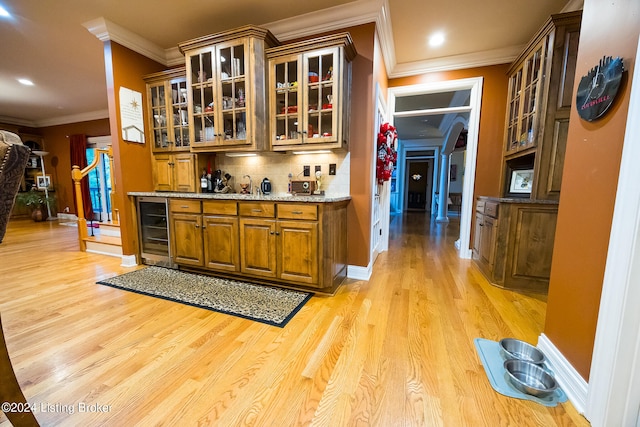 bar with backsplash, wine cooler, ornamental molding, light hardwood / wood-style floors, and light stone counters