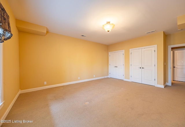 unfurnished bedroom featuring carpet flooring and two closets