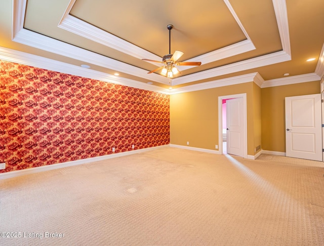 carpeted empty room with a tray ceiling, ceiling fan, and ornamental molding