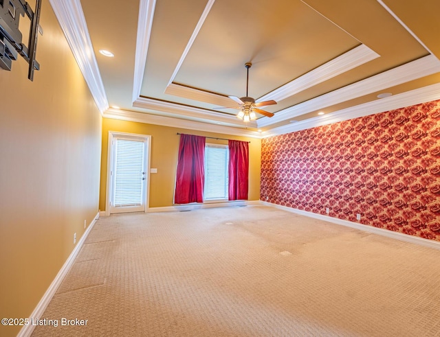 carpeted spare room featuring a tray ceiling, ceiling fan, and ornamental molding