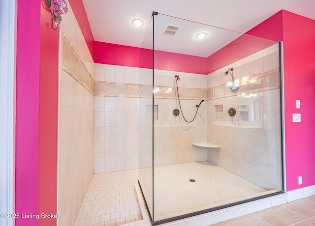 bathroom with tile patterned flooring and a tile shower