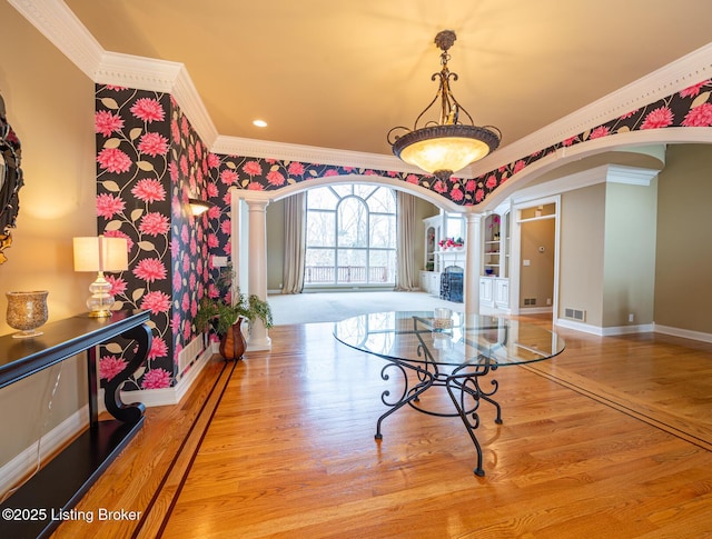 interior space with decorative columns, light hardwood / wood-style flooring, and ornamental molding