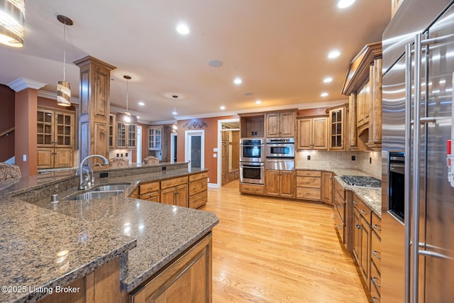 kitchen featuring decorative backsplash, dark stone counters, stainless steel appliances, sink, and pendant lighting