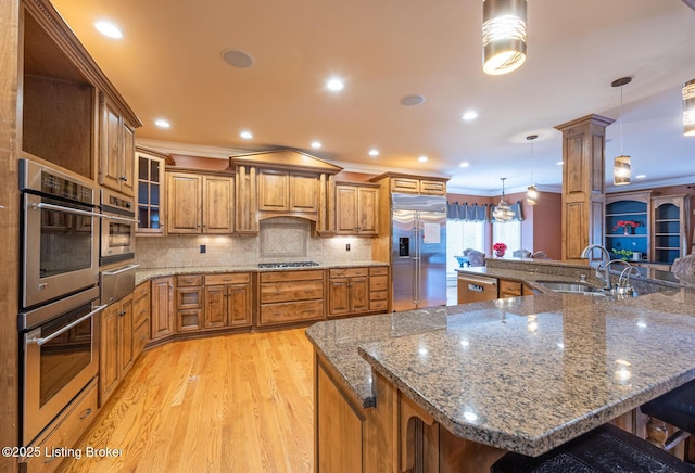 kitchen with ornamental molding, appliances with stainless steel finishes, tasteful backsplash, decorative light fixtures, and a kitchen bar