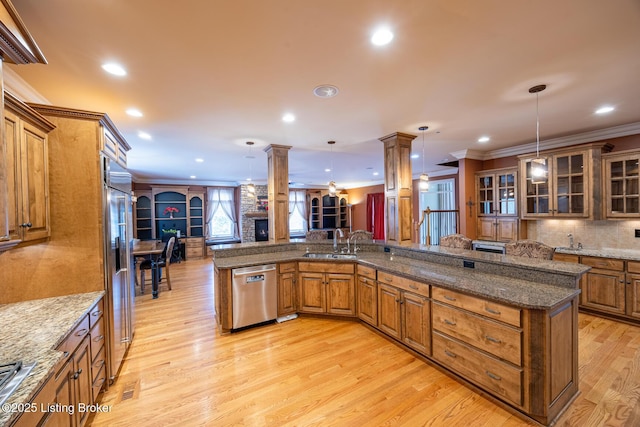 kitchen with decorative light fixtures, stainless steel appliances, crown molding, and decorative columns