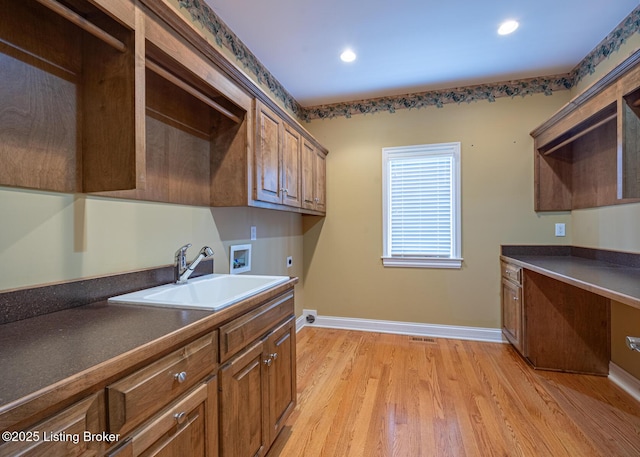 washroom with sink, cabinets, hookup for an electric dryer, light hardwood / wood-style flooring, and hookup for a washing machine