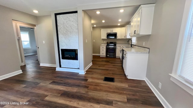 kitchen featuring white cabinets, sink, black range with gas cooktop, and dark wood-type flooring