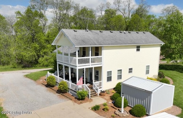 back of house with a balcony, a porch, and a lawn