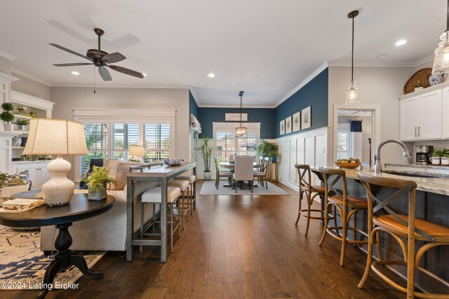 kitchen featuring hanging light fixtures, ornamental molding, white cabinetry, a kitchen breakfast bar, and dark hardwood / wood-style floors