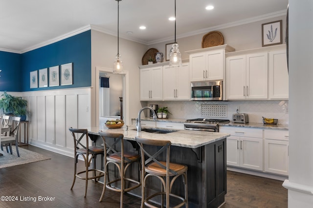 kitchen with white cabinets, a kitchen island with sink, decorative light fixtures, appliances with stainless steel finishes, and dark hardwood / wood-style floors