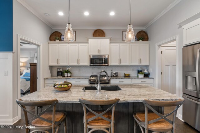 kitchen with stainless steel appliances, hanging light fixtures, sink, and white cabinetry