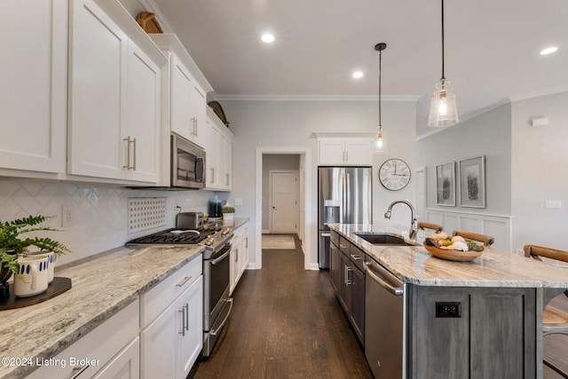 kitchen with an island with sink, white cabinetry, stainless steel appliances, a kitchen bar, and dark hardwood / wood-style flooring