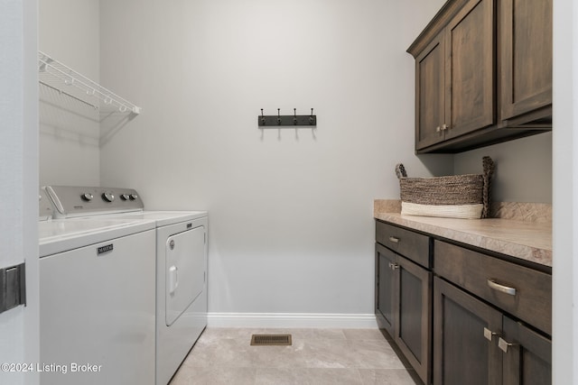 laundry area featuring cabinets, separate washer and dryer, and light tile patterned floors