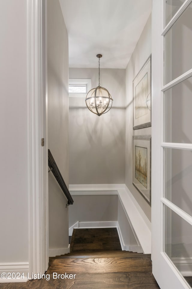 stairs with hardwood / wood-style floors and a chandelier