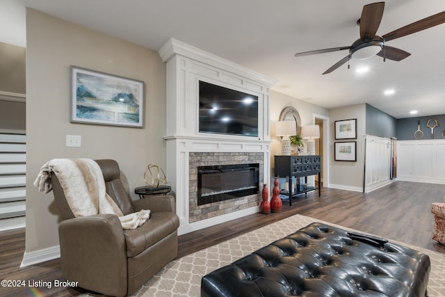 living room with ceiling fan, a fireplace, and dark hardwood / wood-style flooring