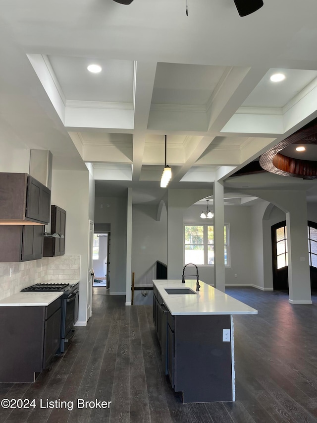 kitchen featuring coffered ceiling, black gas range, dark wood-type flooring, sink, and an island with sink