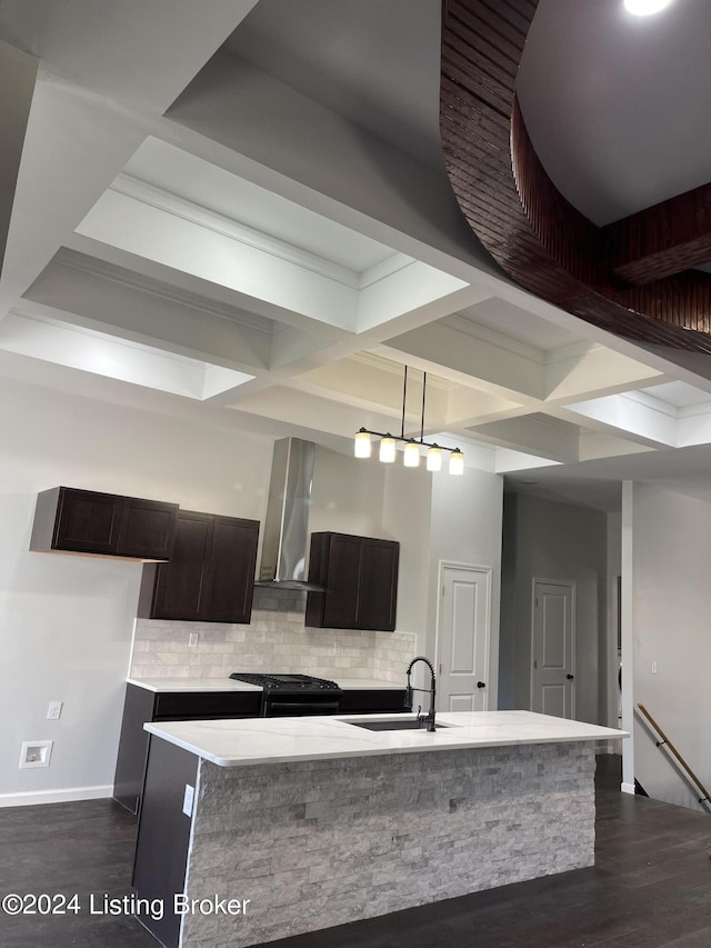 kitchen featuring wall chimney exhaust hood, black gas range oven, tasteful backsplash, a center island with sink, and sink