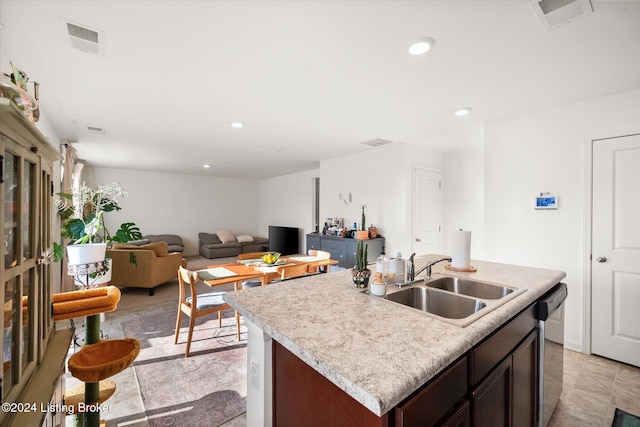 kitchen featuring dark brown cabinetry, an island with sink, sink, and stainless steel dishwasher