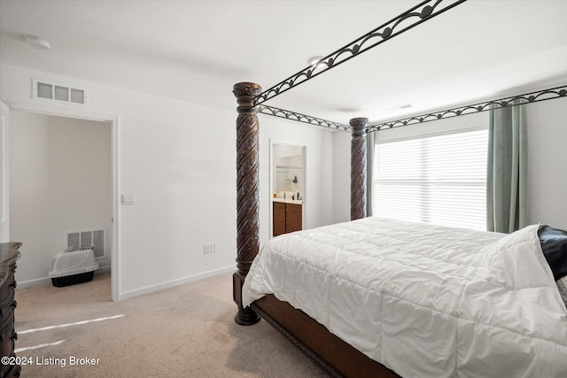 bedroom with connected bathroom and light colored carpet