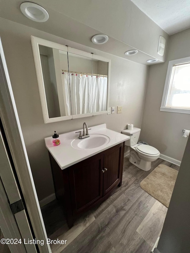 bathroom with a shower with shower curtain, hardwood / wood-style floors, vanity, and toilet